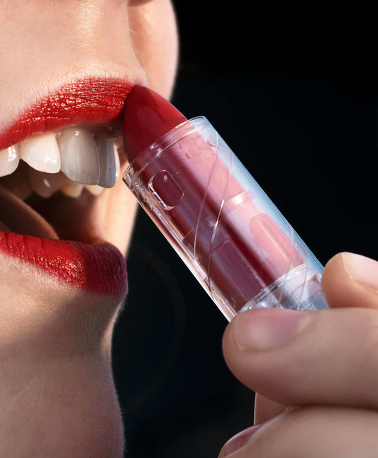 white teeth and lips with red lipstick on them and a hand holding the lipstick to their lips.